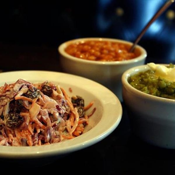 Coleslaw, baked beans, and mushy peas with butter, classic sides for fish and chips.
