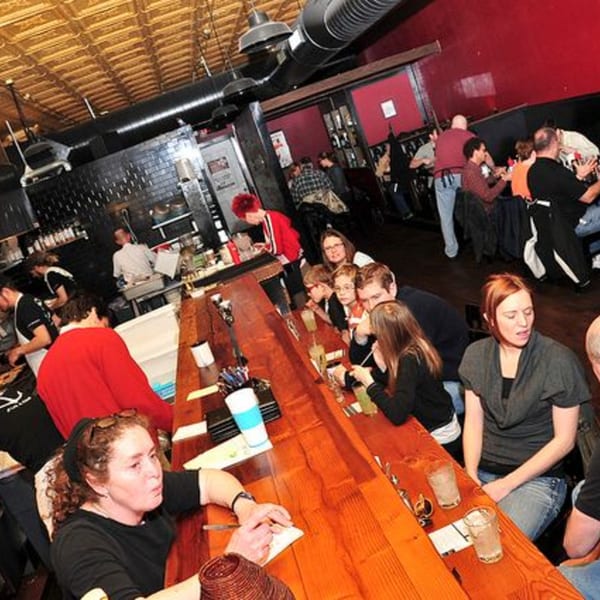 Diners and staff fill The Anchor Fish & Chips, with people seated at a long wooden bar.