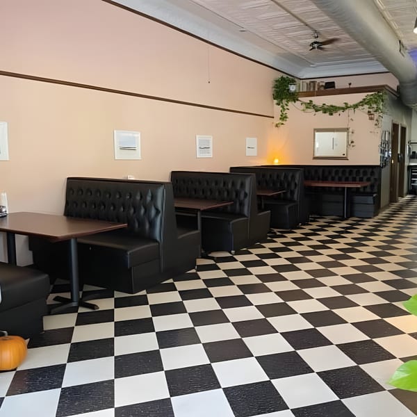 Interior of The Anchor Fish & Chips with black booths, dark tables, and a black and white checkered floor.